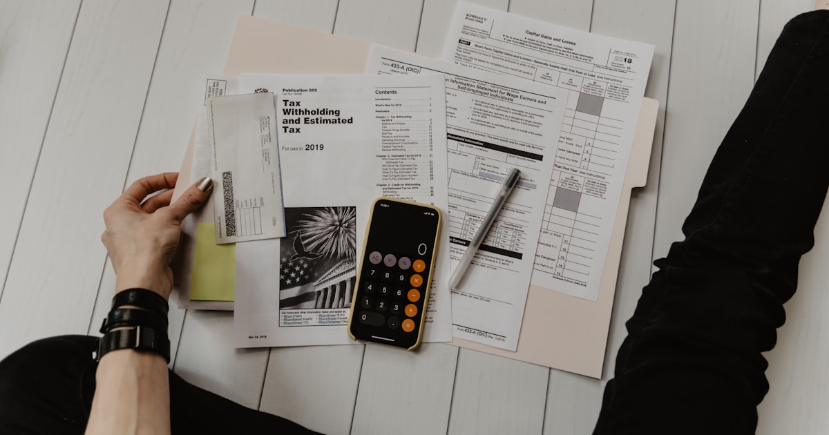 Person reviewing invoices and financial documents with a calculator on a desk — manual invoice processing that IDP replaces